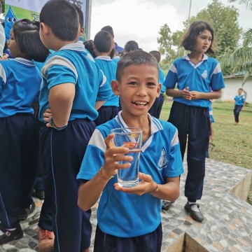 태국의 사캐오 지방의 한 어린이가 와츠와 플래닛 워터 재단이 1000명의 사람들에게 매일 1만 리터의 깨끗한 물을 공급하는 정수 필터 타워를 건설한 후 물 한잔을 즐기고 있다. ⓒ 플래닛 워터 재단